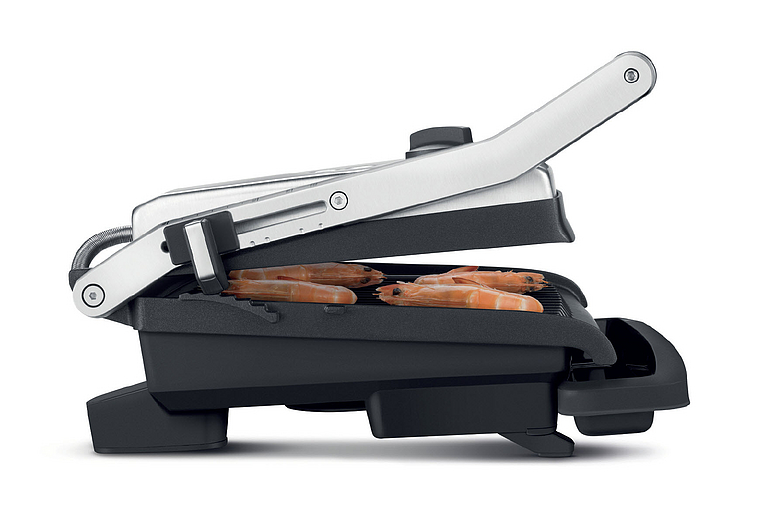 Eine Panini-Presse mit gegrillten Garnelen im Inneren, der Deckel ist offen.