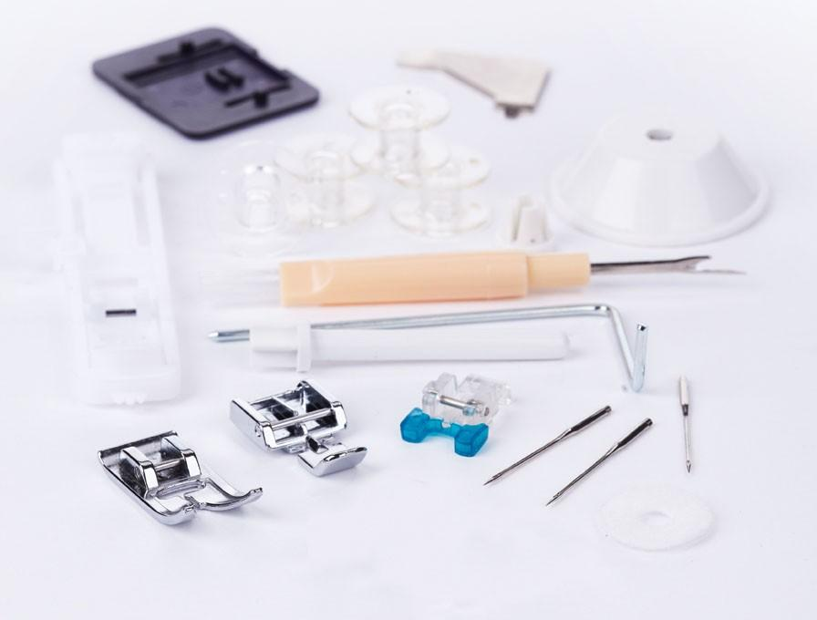 Accesorios de máquina de coser: bobinas, agujas, un desgarrador de costuras, prensatelas y otras piezas pequeñas.