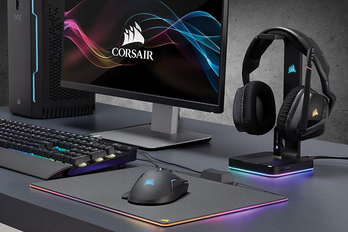 Configuración de juego con PC, monitor, ratón, teclado y auriculares en escritorio oscuro.