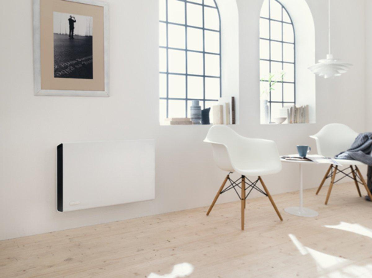 Salón con paredes blancas, dos sillas y un calefactor en la pared. Obra de arte y ventanas presentes.