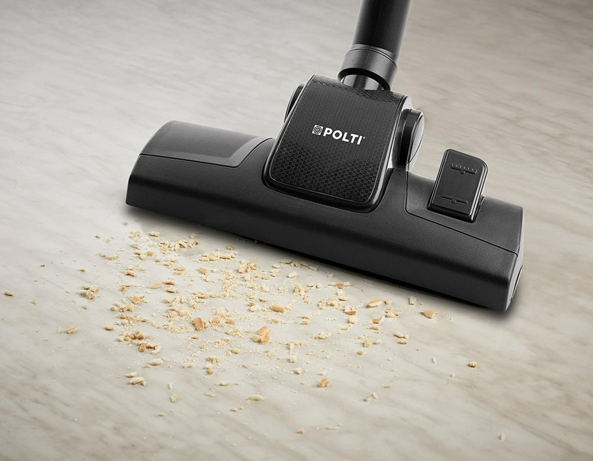 Cabezal de aspiradora en un piso de madera, limpiando migas.