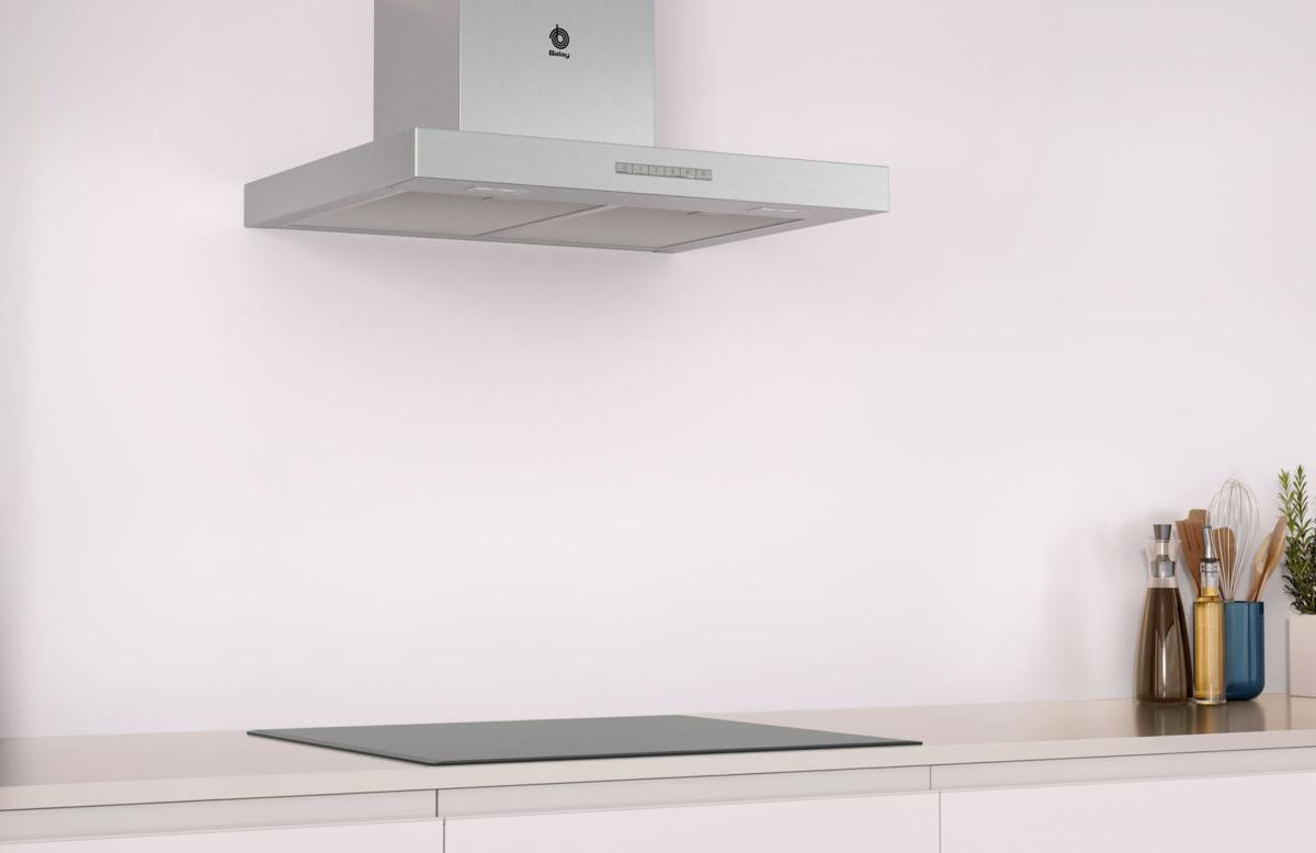 Una escena de cocina con una campana de acero inoxidable, una estufa y una encimera blanca.
