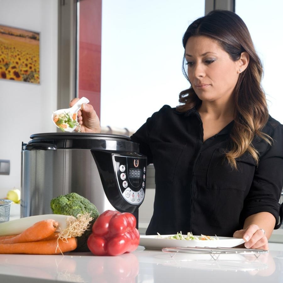 Mujer poniendo verduras en olla a presión, ingredientes en encimera.
