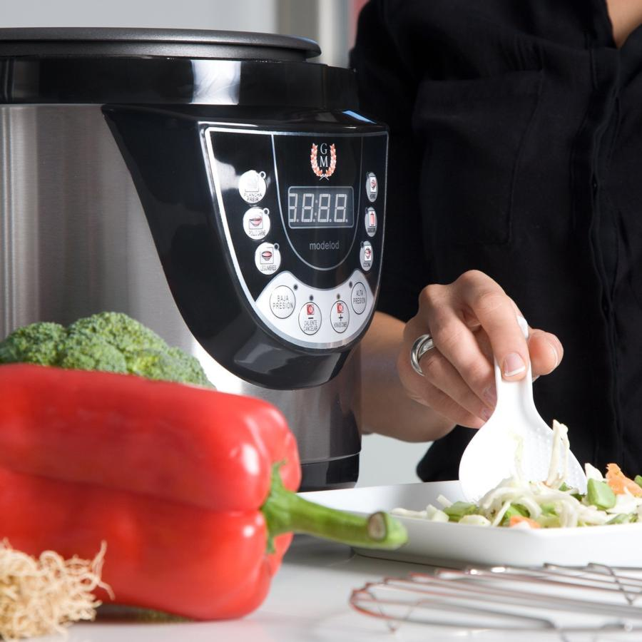 Una persona usa una cuchara para remover comida en un bol blanco junto a una olla a presión, pimiento rojo y brócoli.