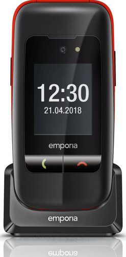 Téléphone à clapet noir avec des touches de rouge. Affiche l'heure et la date. Il est dans son socle de chargement.