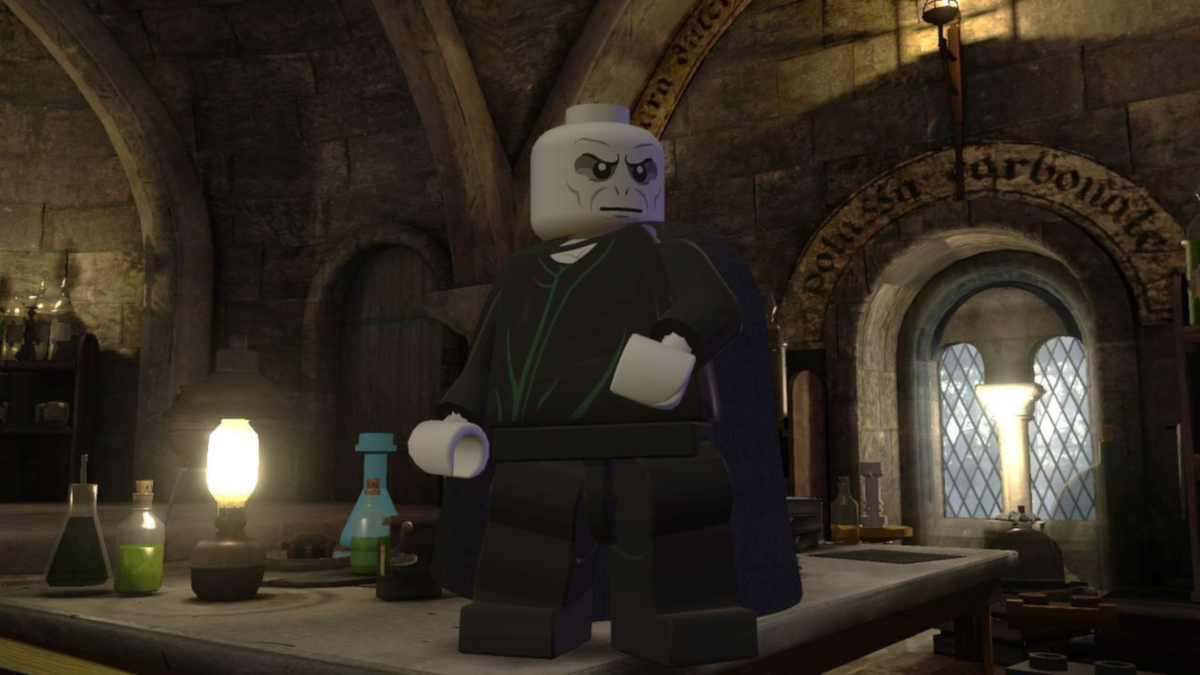 Eine Lego-Figur eines kahlen, grauhäutigen Mannes in einem dunklen Umhang, der in einem Steinraum steht.