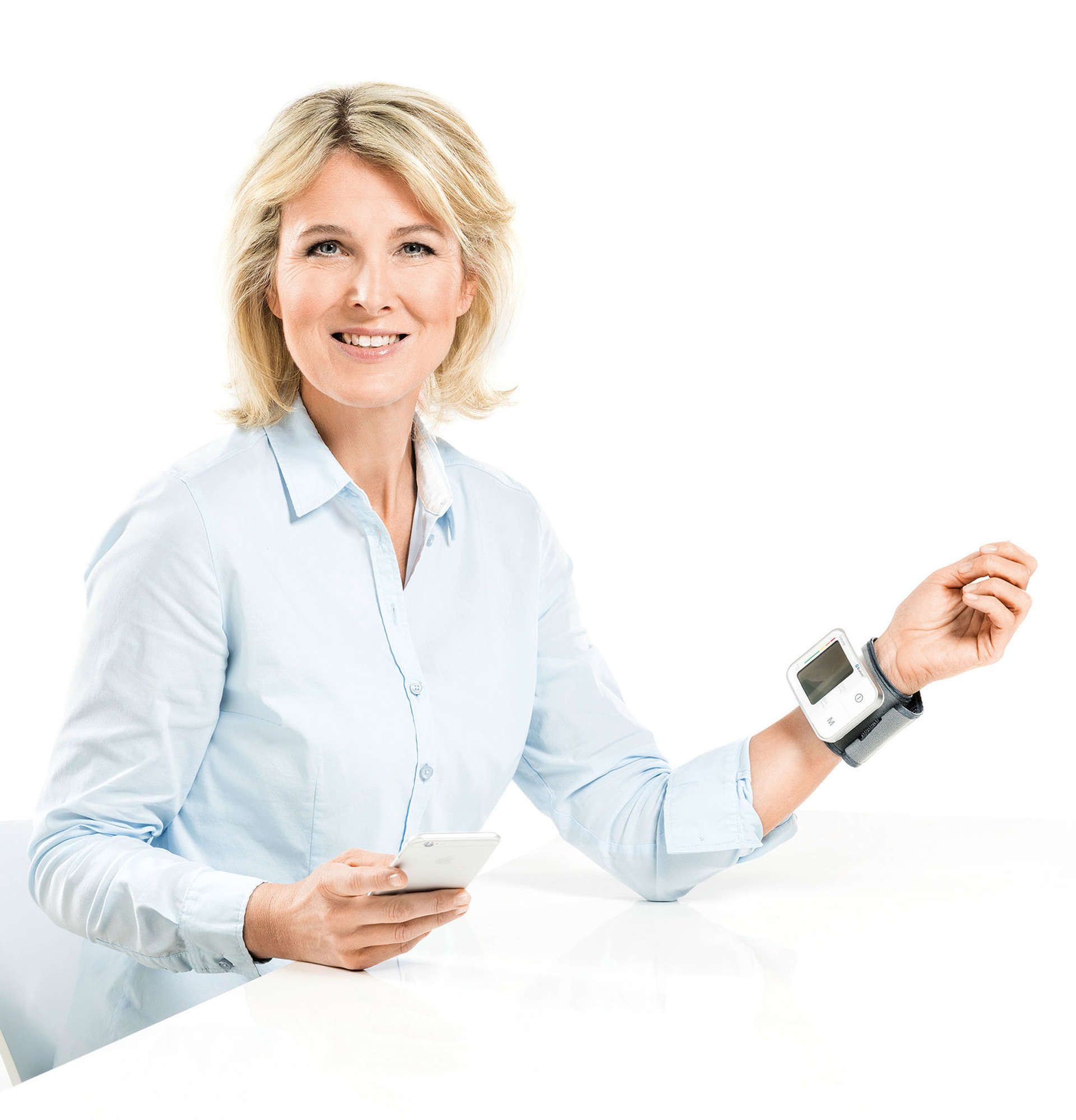 Vrouw met telefoon en bloeddrukmeter om de pols. Witte achtergrond.