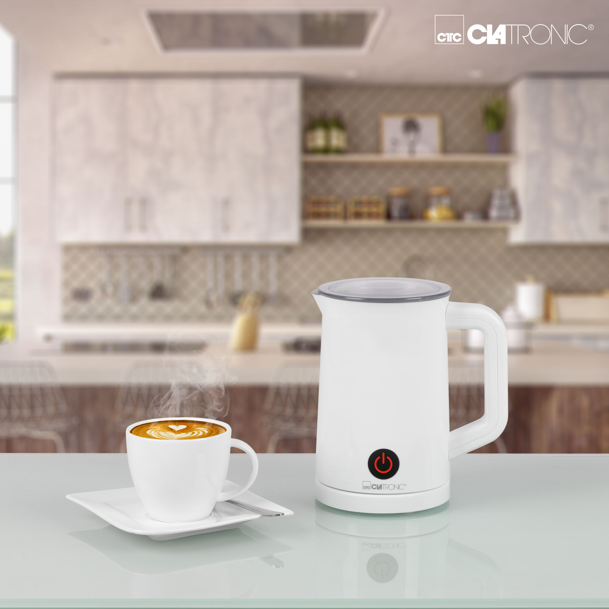Eine weiße Kaffeemaschine und eine Tasse Kaffee auf weißer Oberfläche. Eine Küche im verschwommenen Hintergrund.