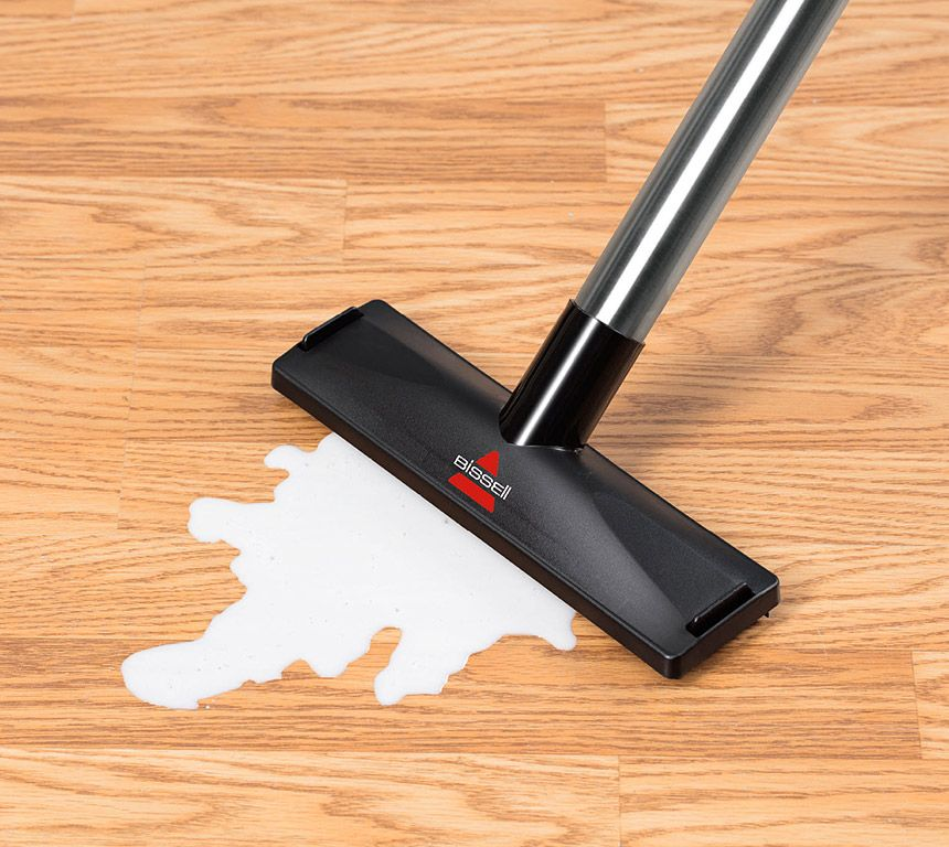Stofzuigerkop op hardhouten vloer met een witte vloeistof.
