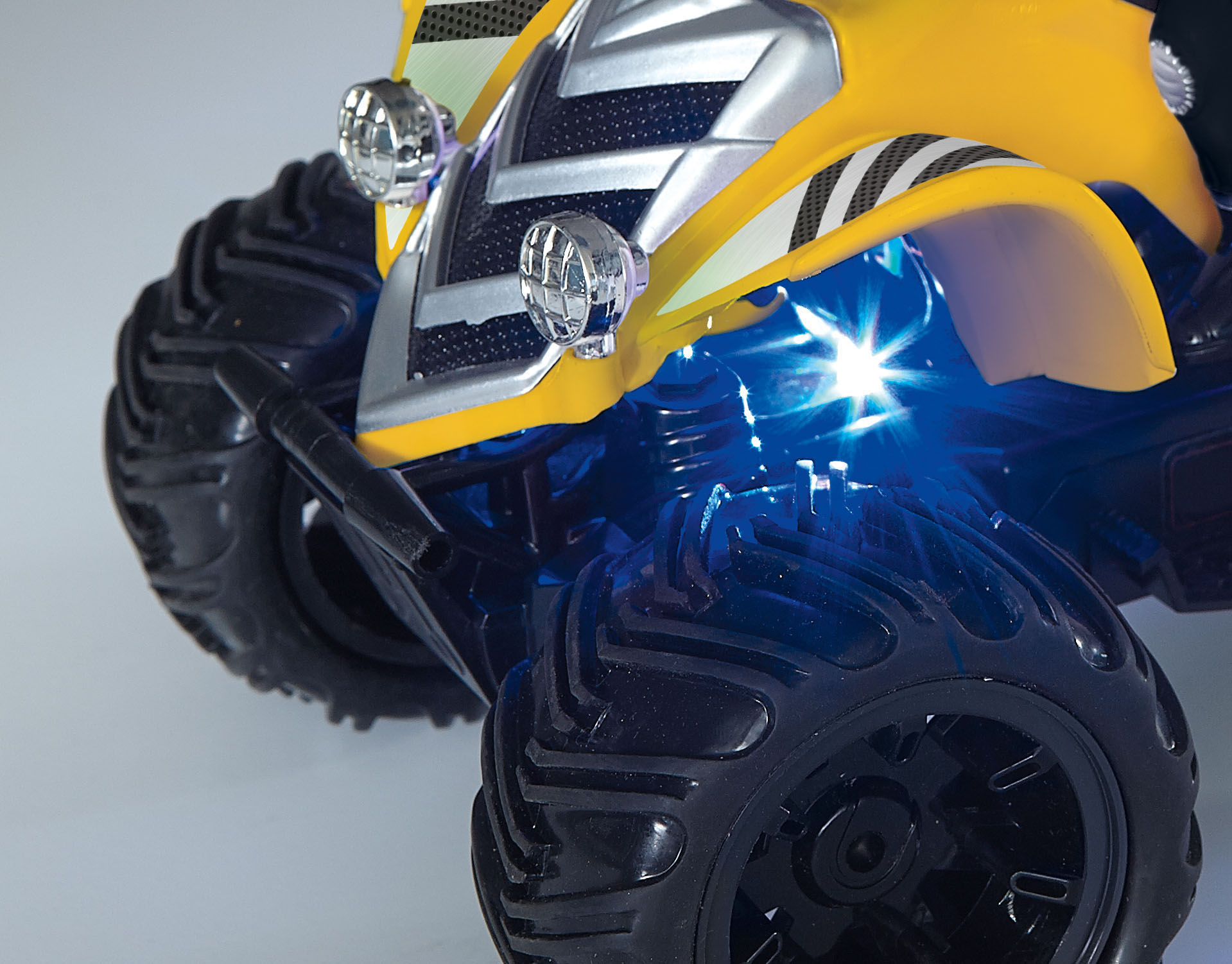 Gelb-schwarzes Spielzeug-Monstertruck mit blauen Lichtern und großen schwarzen Reifen. Nahaufnahme.