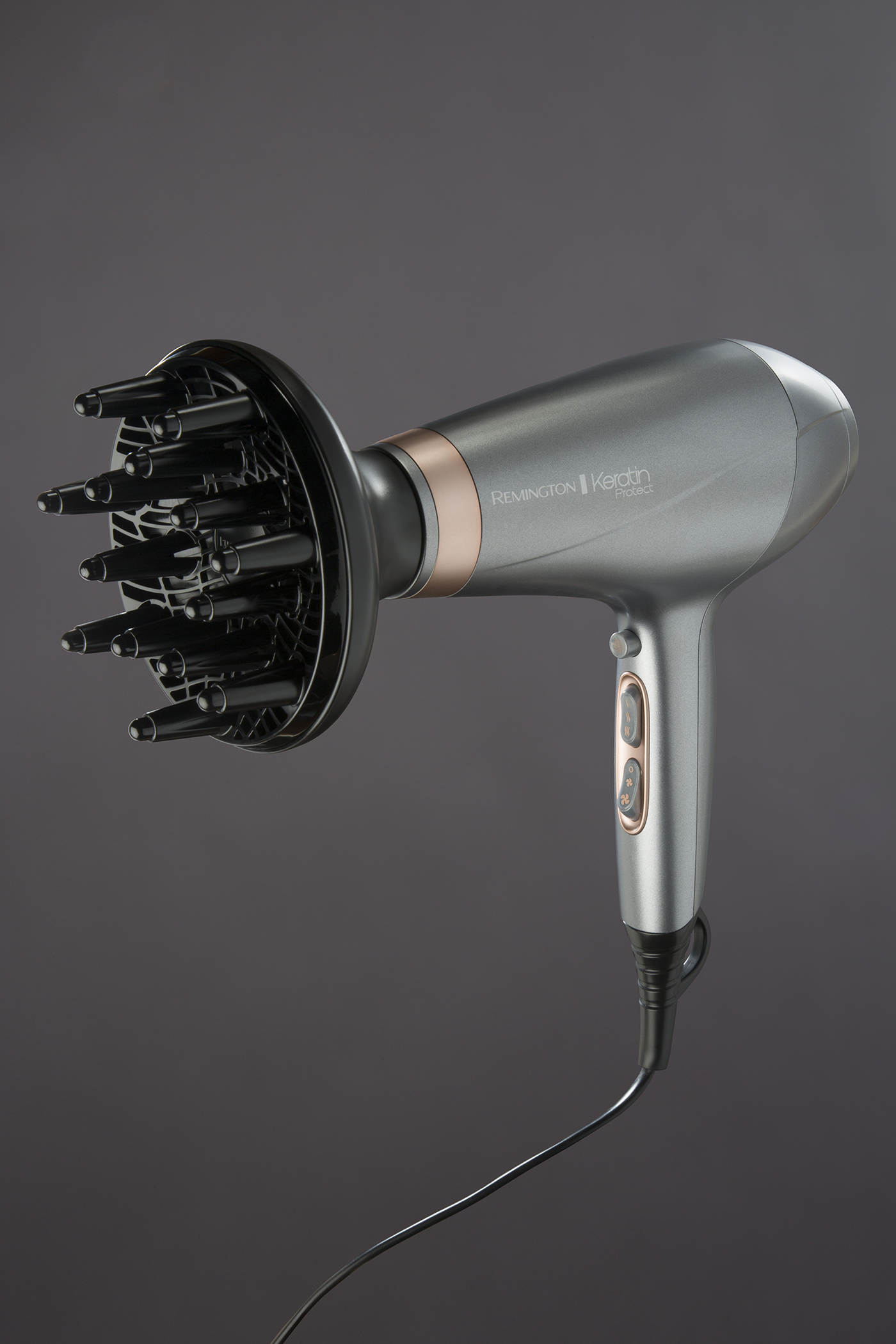 A gray hair dryer with a diffuser attachment. It is on a dark gray background.