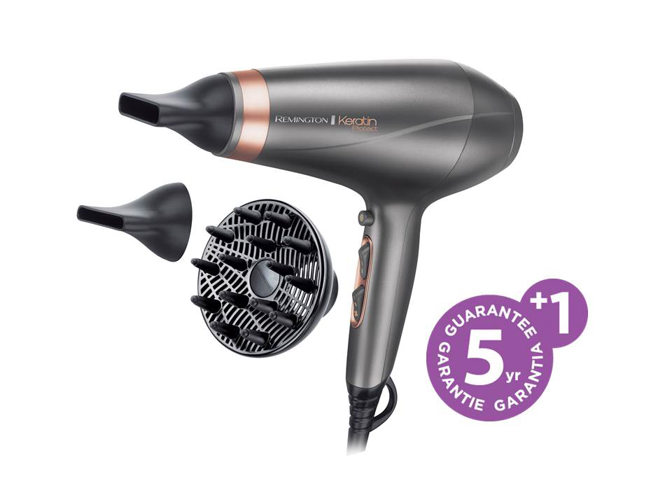 A gray Remington hair dryer with attachments and a 5-year guarantee sticker. White background.