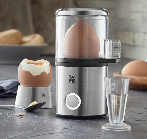 Hervidor de huevos con un huevo dentro. Otro huevo cocido sobre un soporte. Escena de cocina.