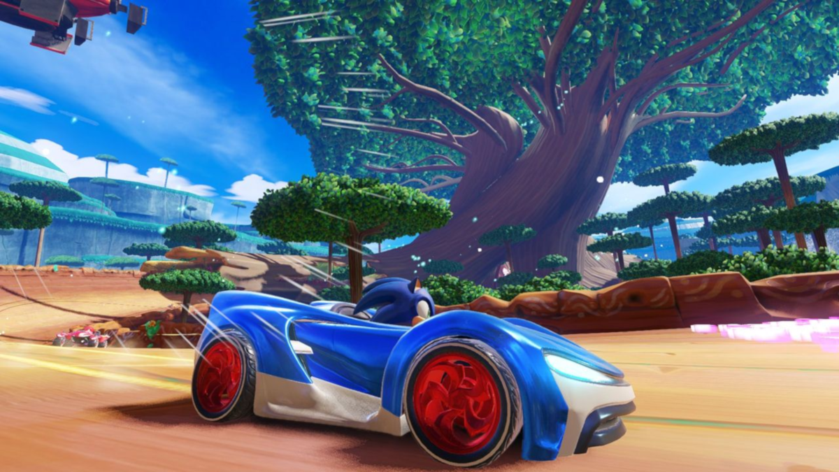 Sonic le Hérisson conduisant une voiture de course bleue sur une piste. Ciel bleu et grand arbre en arrière-plan.