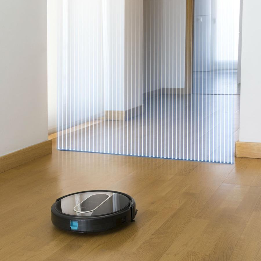 Una aspiradora robótica en un piso de madera, con rayas de luz que indican movimiento en el fondo.