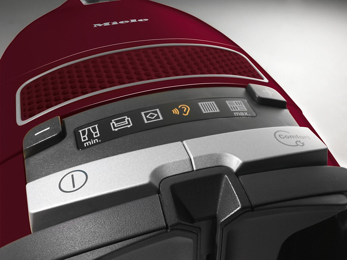 Una aspiradora Miele roja con panel de control, que muestra diferentes modos de limpieza.