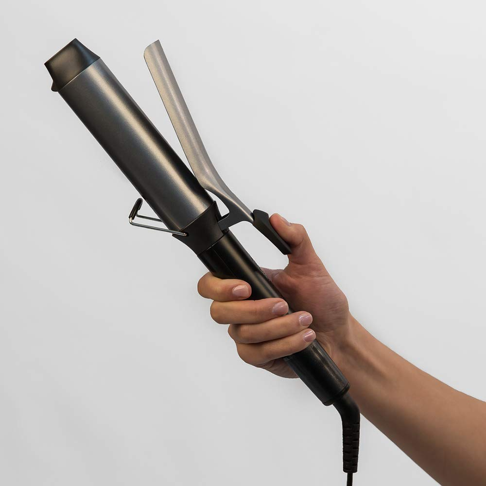 A hand holds a black and silver hair curling iron against a white background.