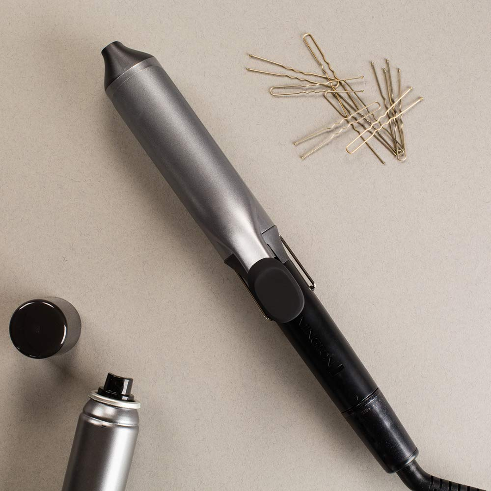 Hair curler, pins, and hairspray on a light gray surface, ready for hairstyling.