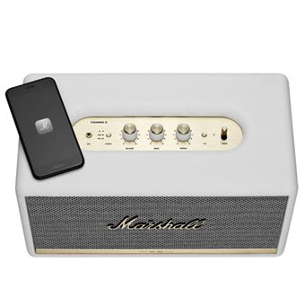 Altavoz Marshall blanco y un smartphone negro. El altavoz tiene controles dorados y una parte frontal de malla.