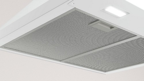 Campana extractora blanca con filtro de malla metálica. El fondo es blanco.