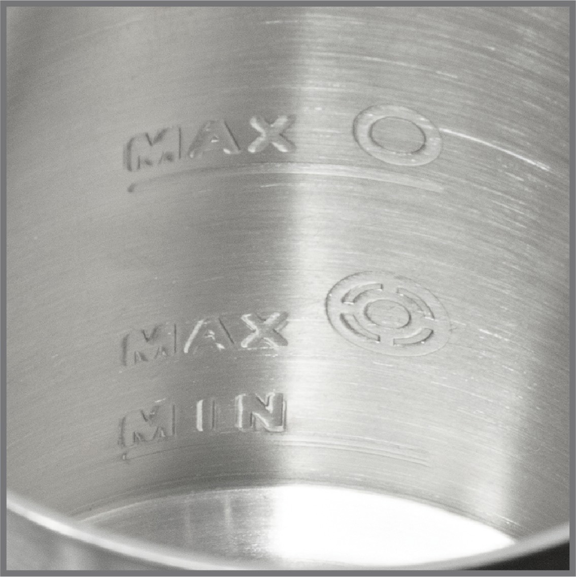 Nahaufnahme eines Metallbehälters mit Markierungen für Max- und Min-Füllstände.