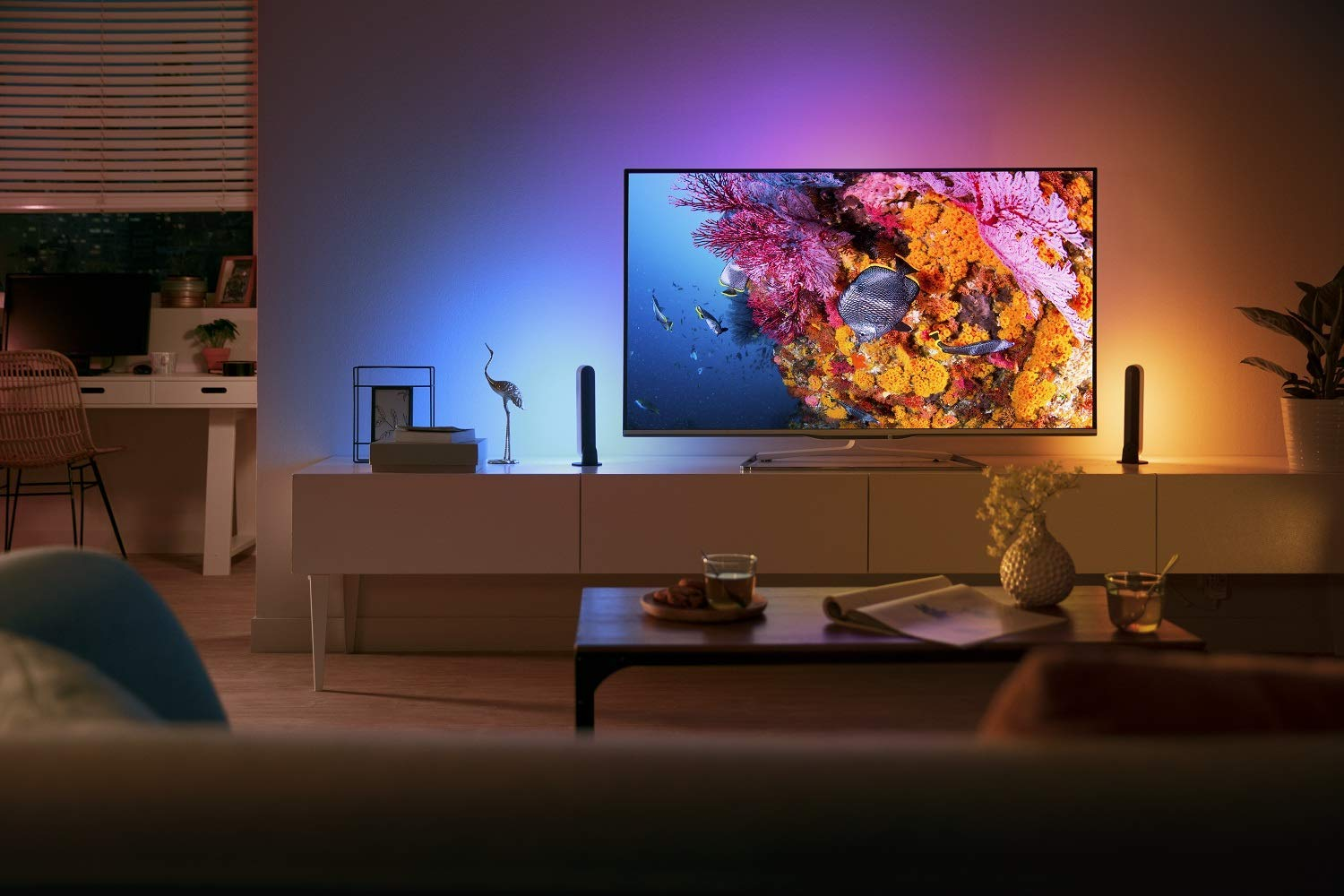 Una escena de sala de estar con un televisor que muestra una imagen colorida, con iluminación ambiental.