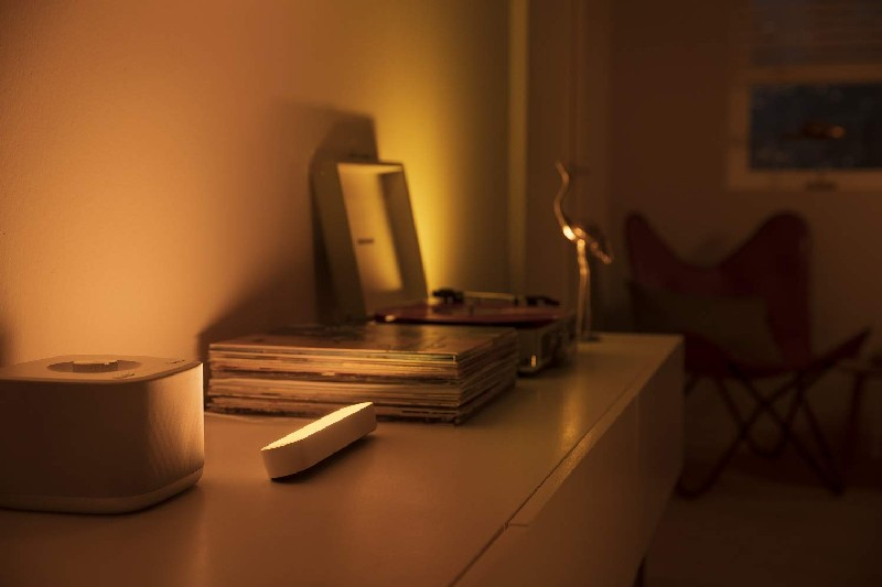 Una estantería con un tocadiscos, discos, una luz y un pájaro decorativo.