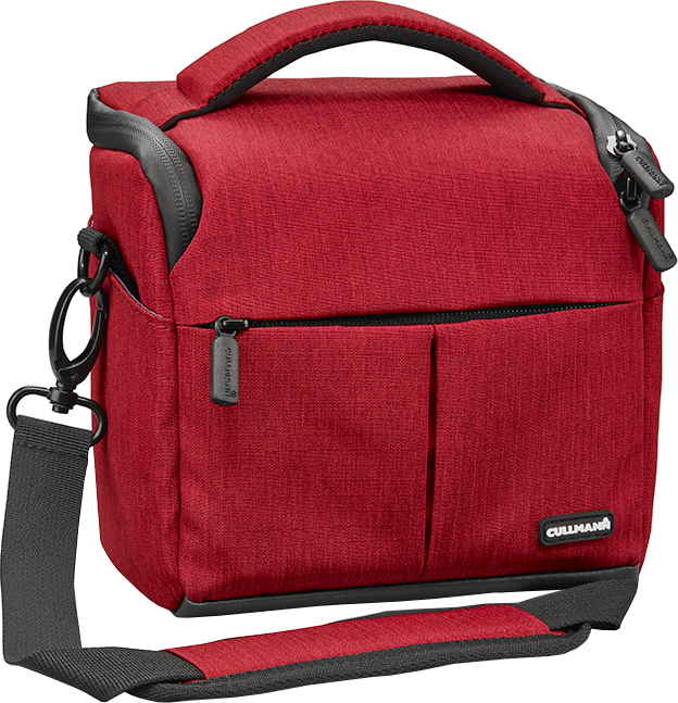 Sac pour appareil photo rouge avec une bandoulière. Il a une poche avant et une poignée noire.