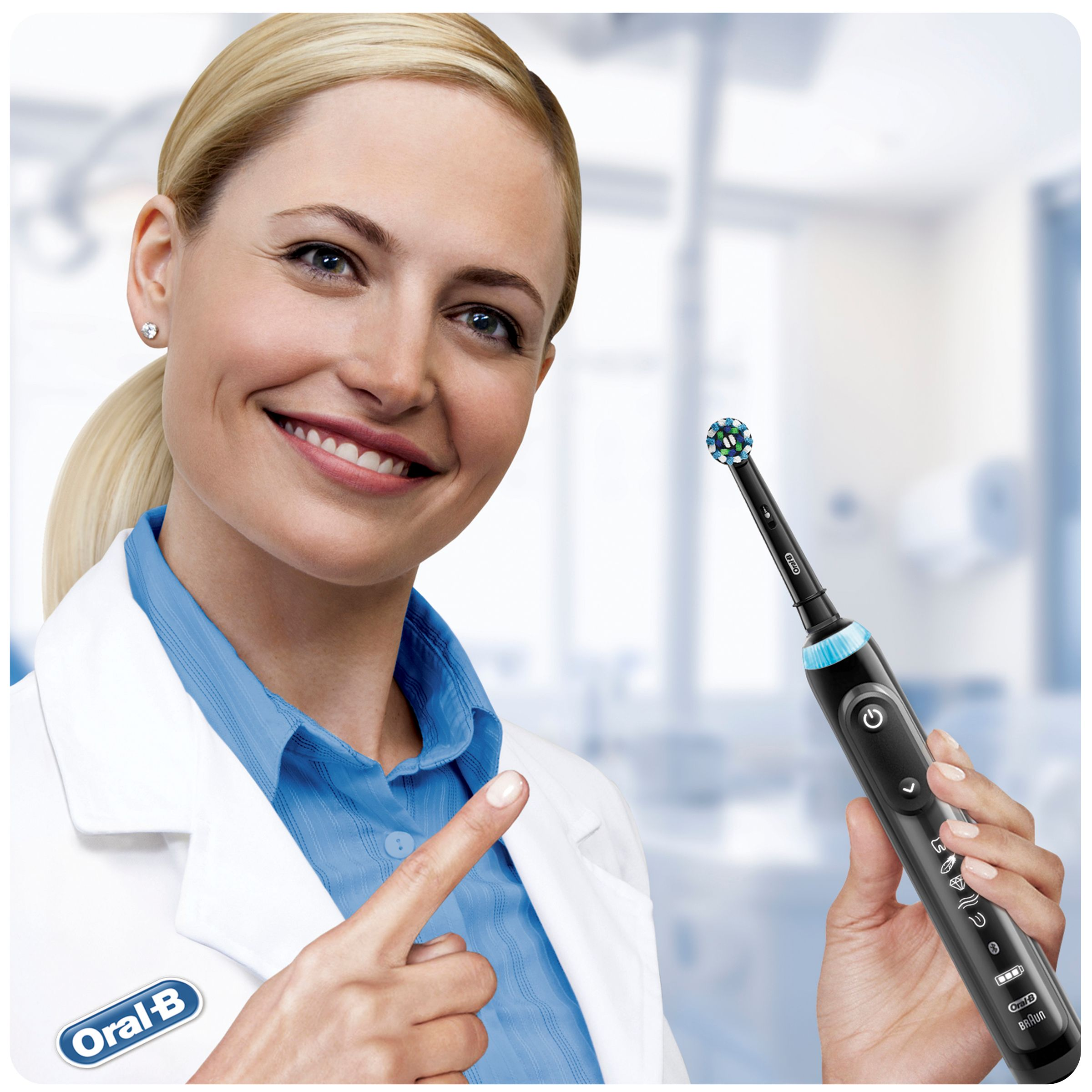 Frau im Laborkittel lächelt, zeigt auf schwarze Oral-B Zahnbürste.