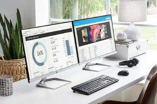Dos monitores de computadora uno al lado del otro en un escritorio blanco, con teclado y ratón.