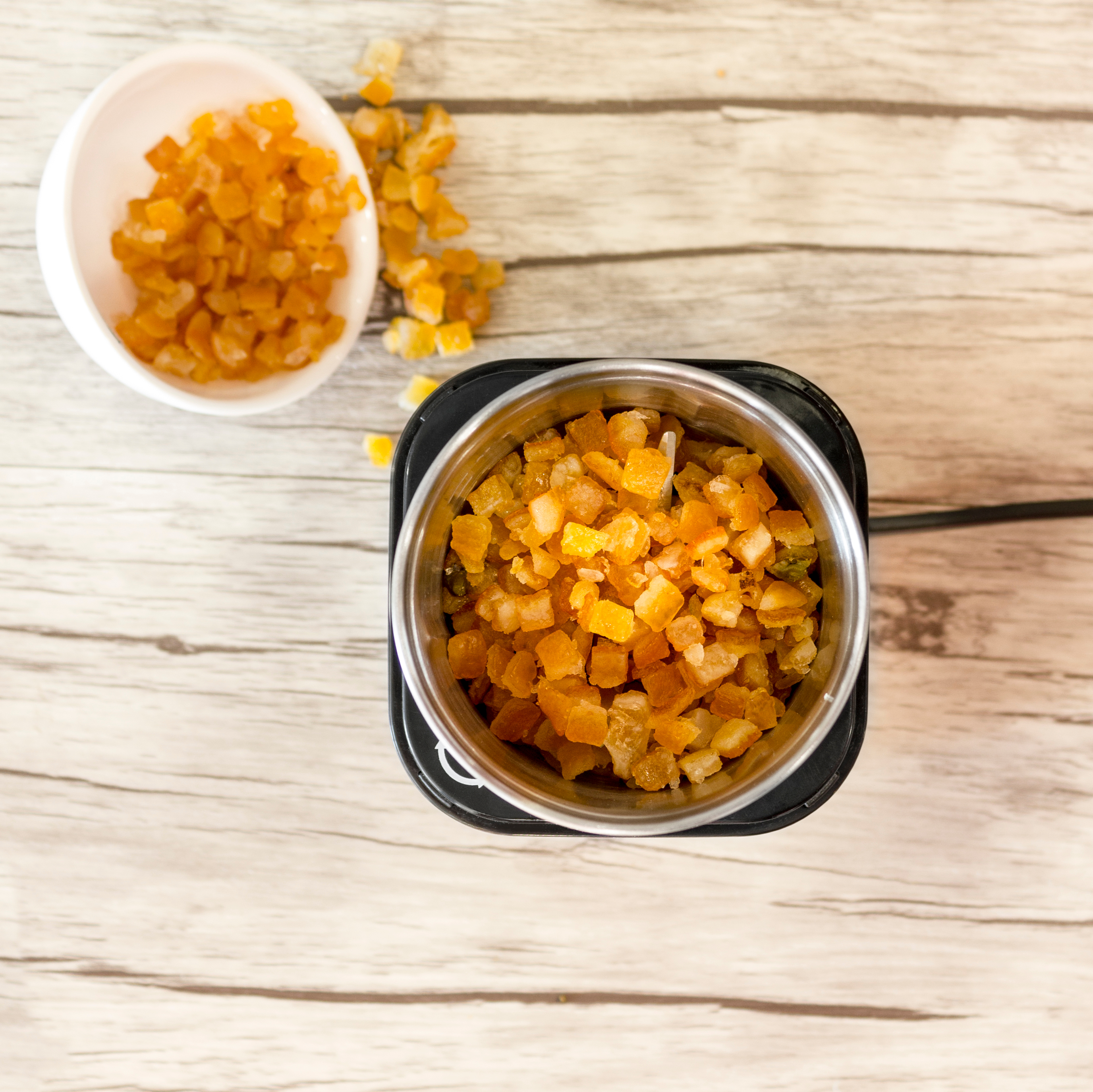 Draufsicht auf gehackte orangefarbene Süßigkeiten in einer Schüssel und einem Mixer.
