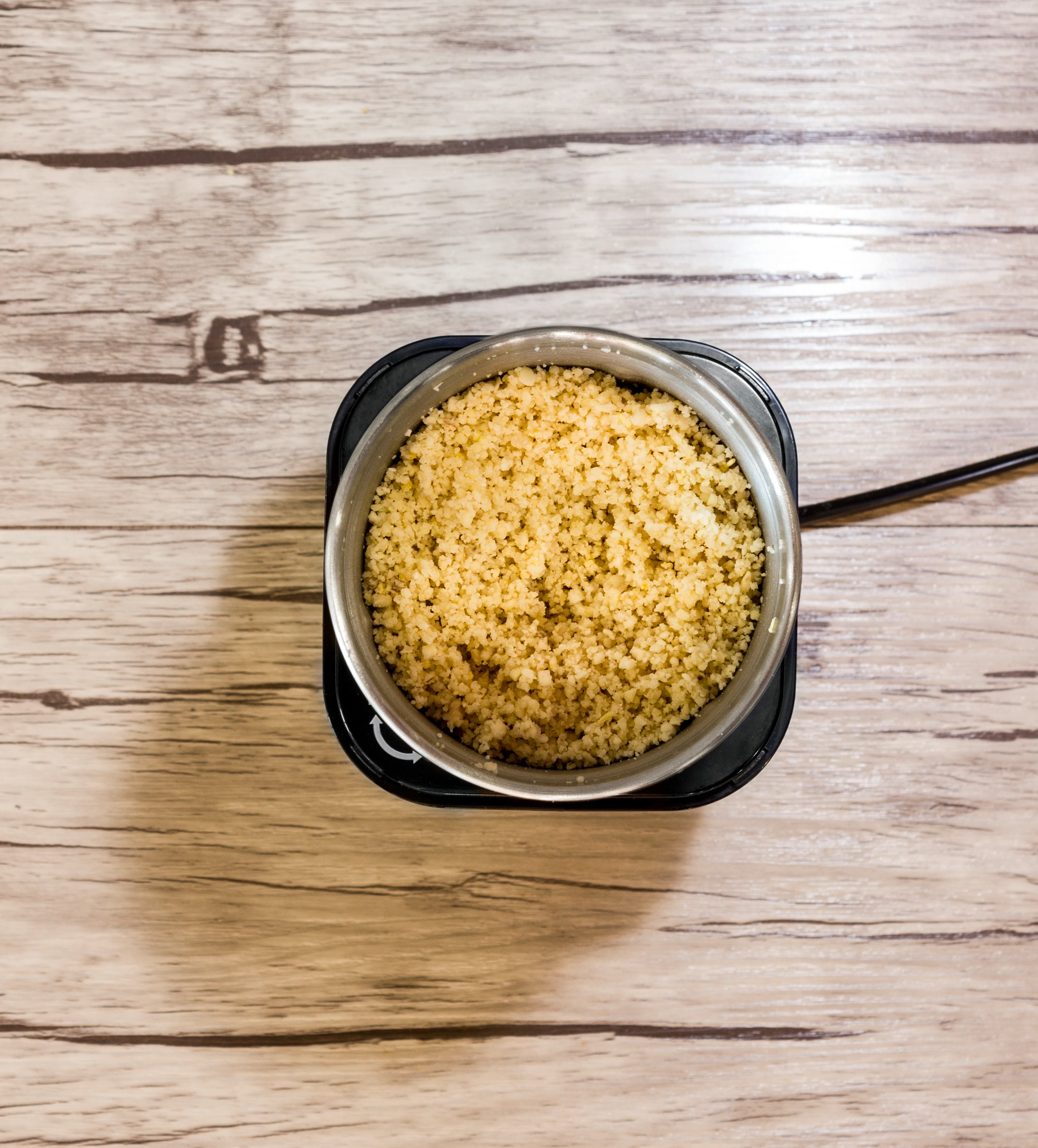 Draufsicht auf Couscous in einer Schüssel auf einer Holzoberfläche.