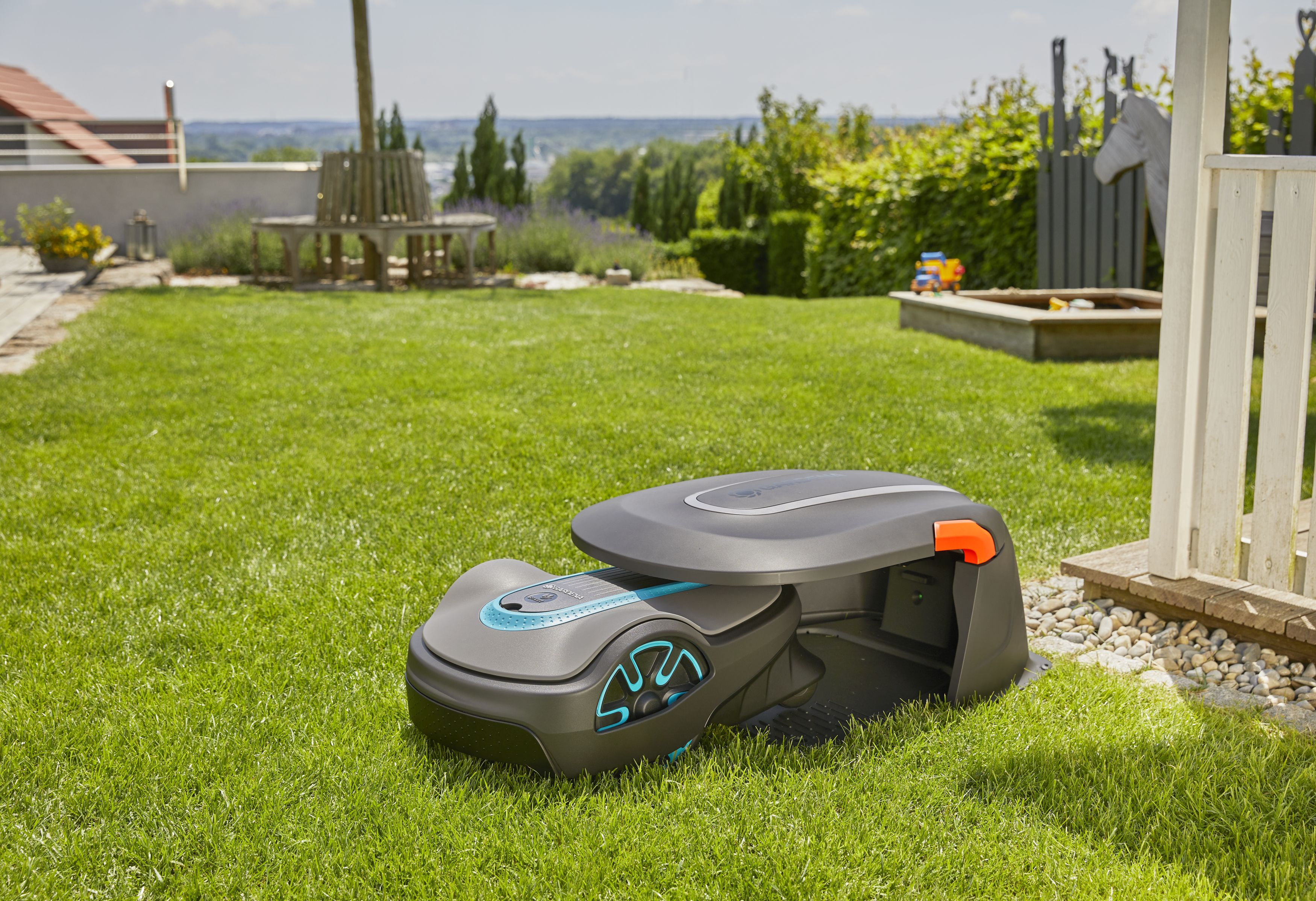 Roboter-Rasenmäher im Garten mit grünem Rasen und Bäumen im Hintergrund.