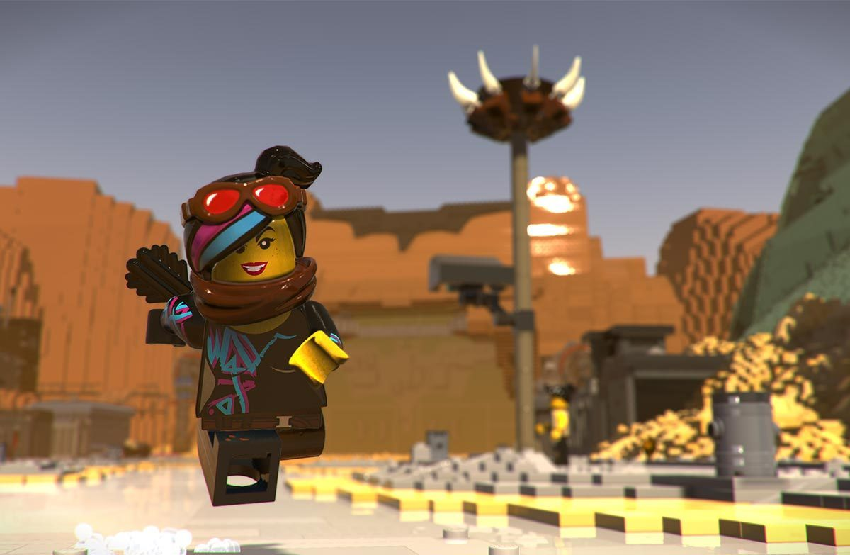 Personaggio LEGO in un paesaggio desertico. La figura è una donna con occhiali, braccia alzate e un sorriso.