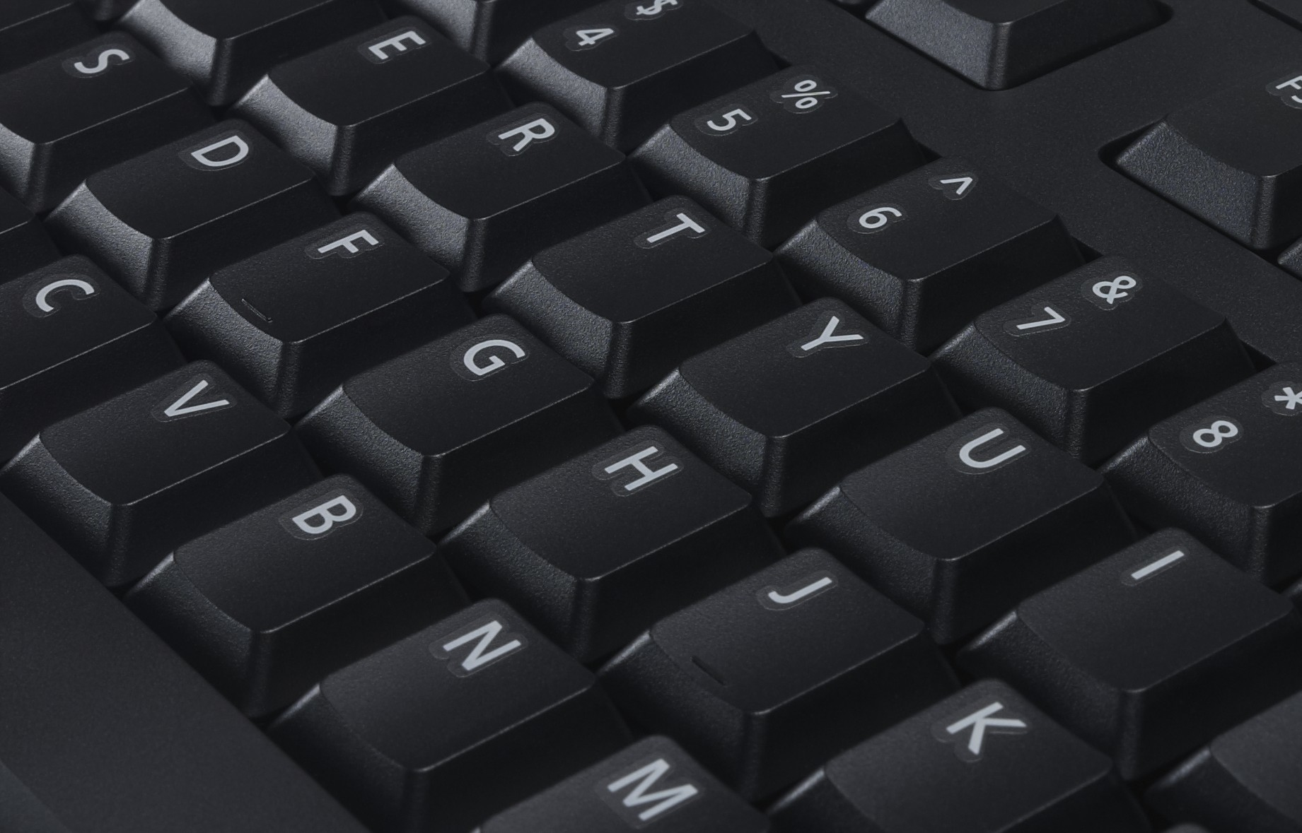 Nahaufnahme einer schwarzen Computertastatur. Tasten mit weißen Buchstaben und Symbolen sind sichtbar. Einige Buchstaben sind F, G, H, Y und U.