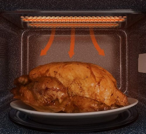 Un pollo asado se encuentra en un plato blanco dentro de un microondas.
