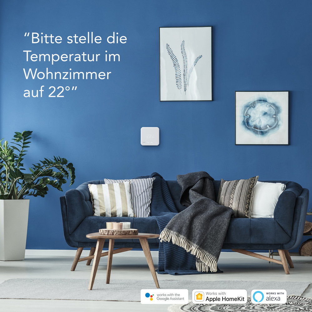 Wohnzimmer mit blauem Sofa, Kunstwerken und Smart-Home-Gerät.