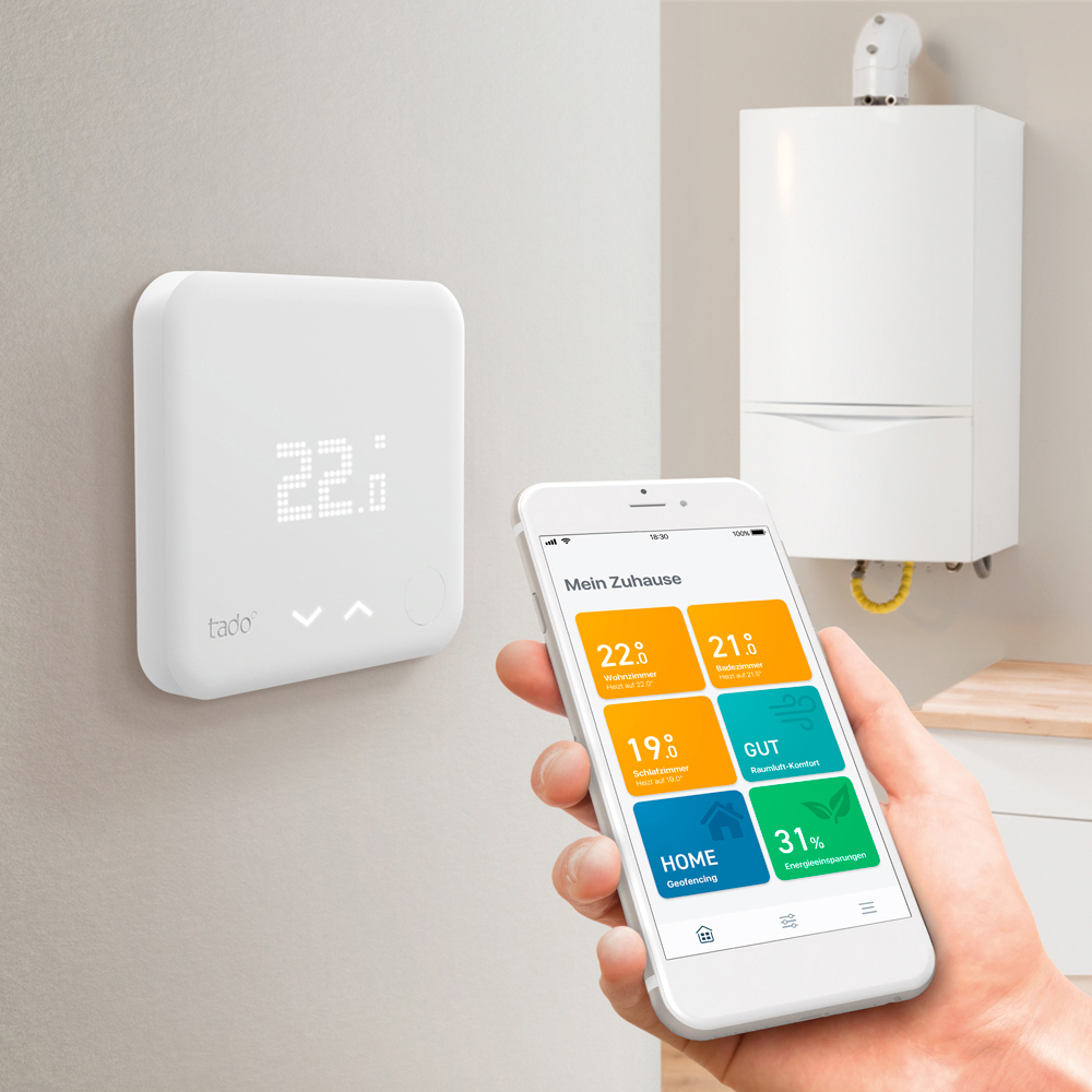 Ein intelligenter Thermostat und Smartphone, das die Benutzeroberfläche zur Temperaturregelung anzeigt.