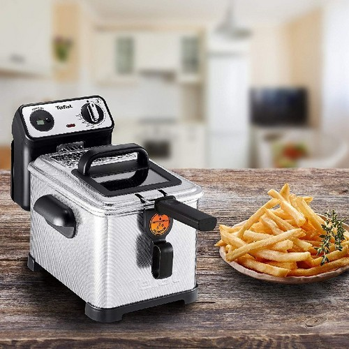Una freidora Tefal plateada con mango y controles negros. Papas fritas en mesa de madera.
