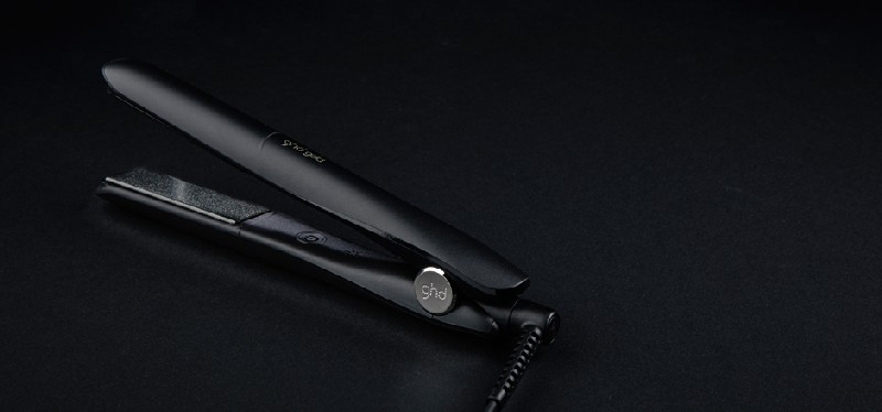 Plancha de pelo negra sobre superficie negra, vista superior, ligeramente abierta.