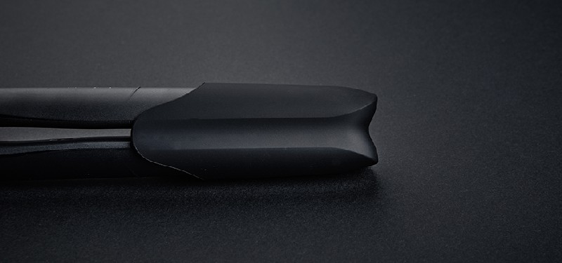 Primer plano de un alisador de pelo negro, forma curva, fondo negro.