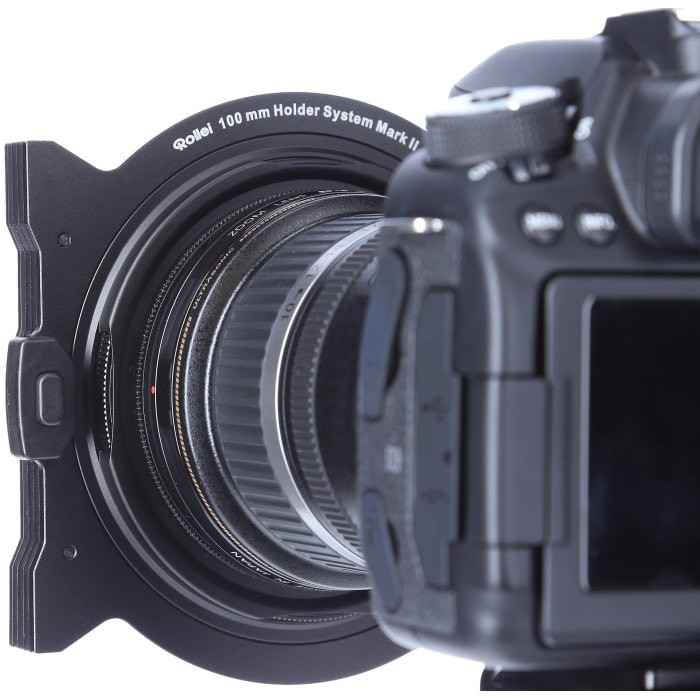 Cameralens met filter bevestigd, gemonteerd op een camerabody, geïsoleerd.