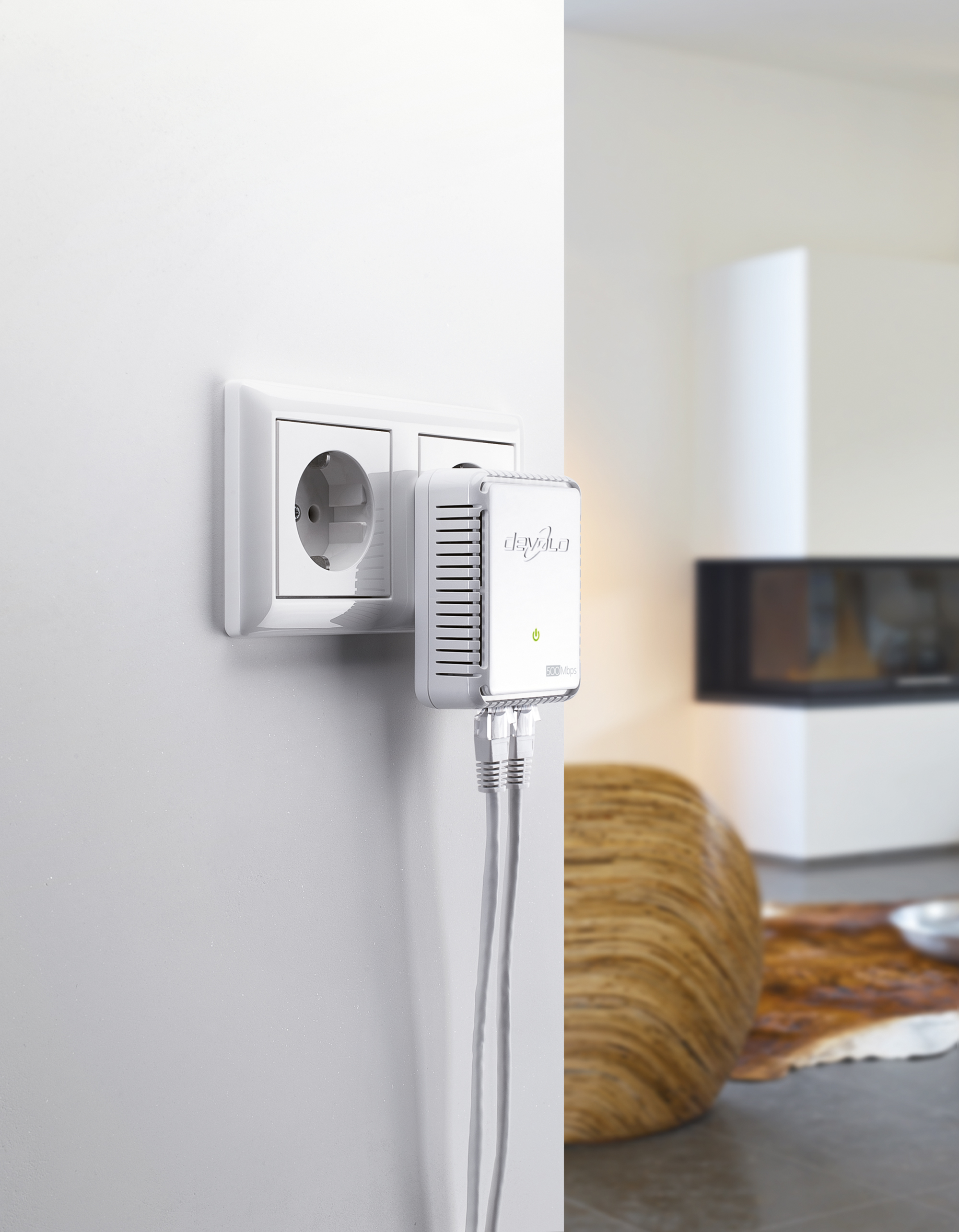 Weißer Powerline-Adapter, der in eine Steckdose mit Ethernet-Kabel gesteckt ist. Die Wand ist weiß, der Hintergrund unscharf.