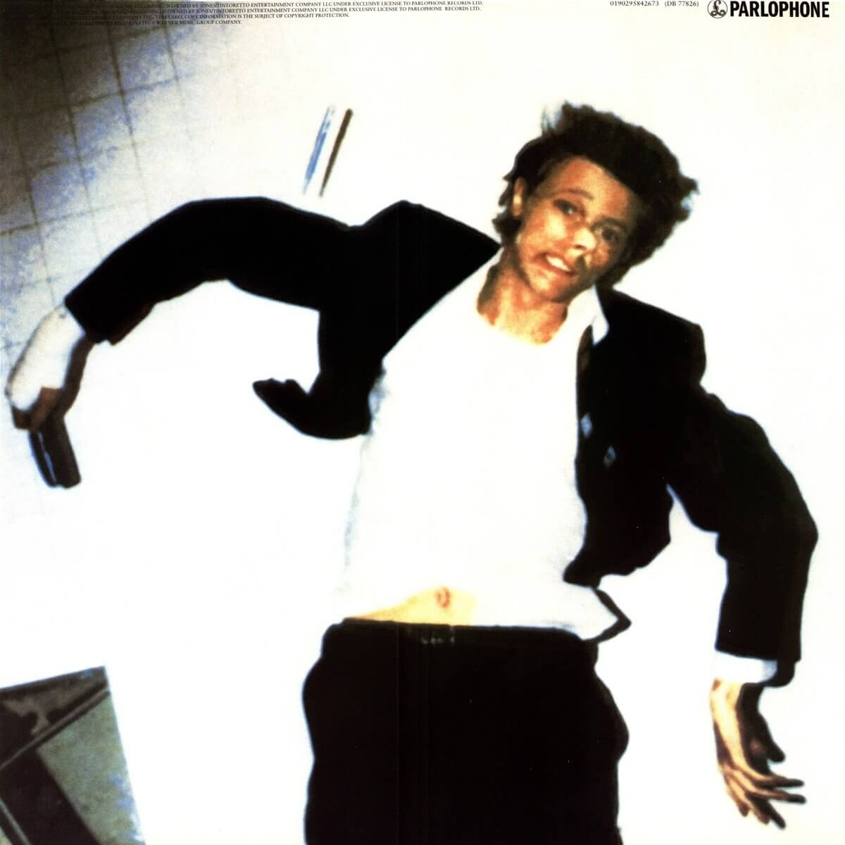 Man in a suit jacket and white shirt, lying on a white background, arms outstretched.