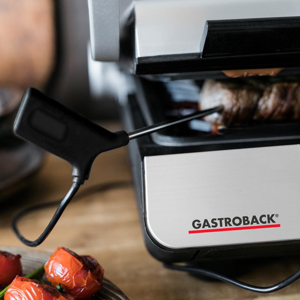 Nahaufnahme eines Grills mit einem Fleischthermometer in einem Steak. Der Markenname Gastroback ist sichtbar.