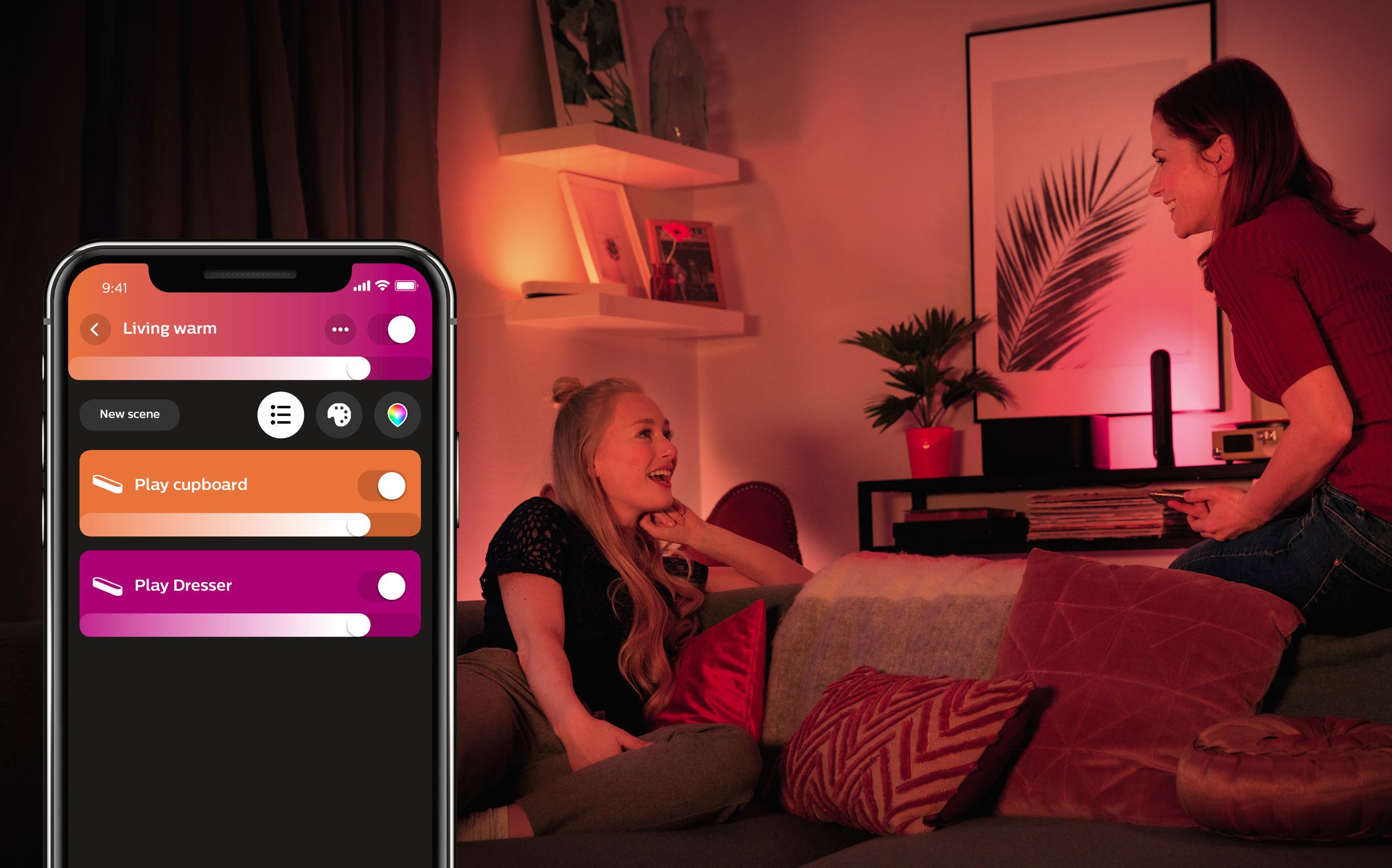 Due donne in soggiorno, una su un divano che usa un telefono con un'app per l'illuminazione intelligente.