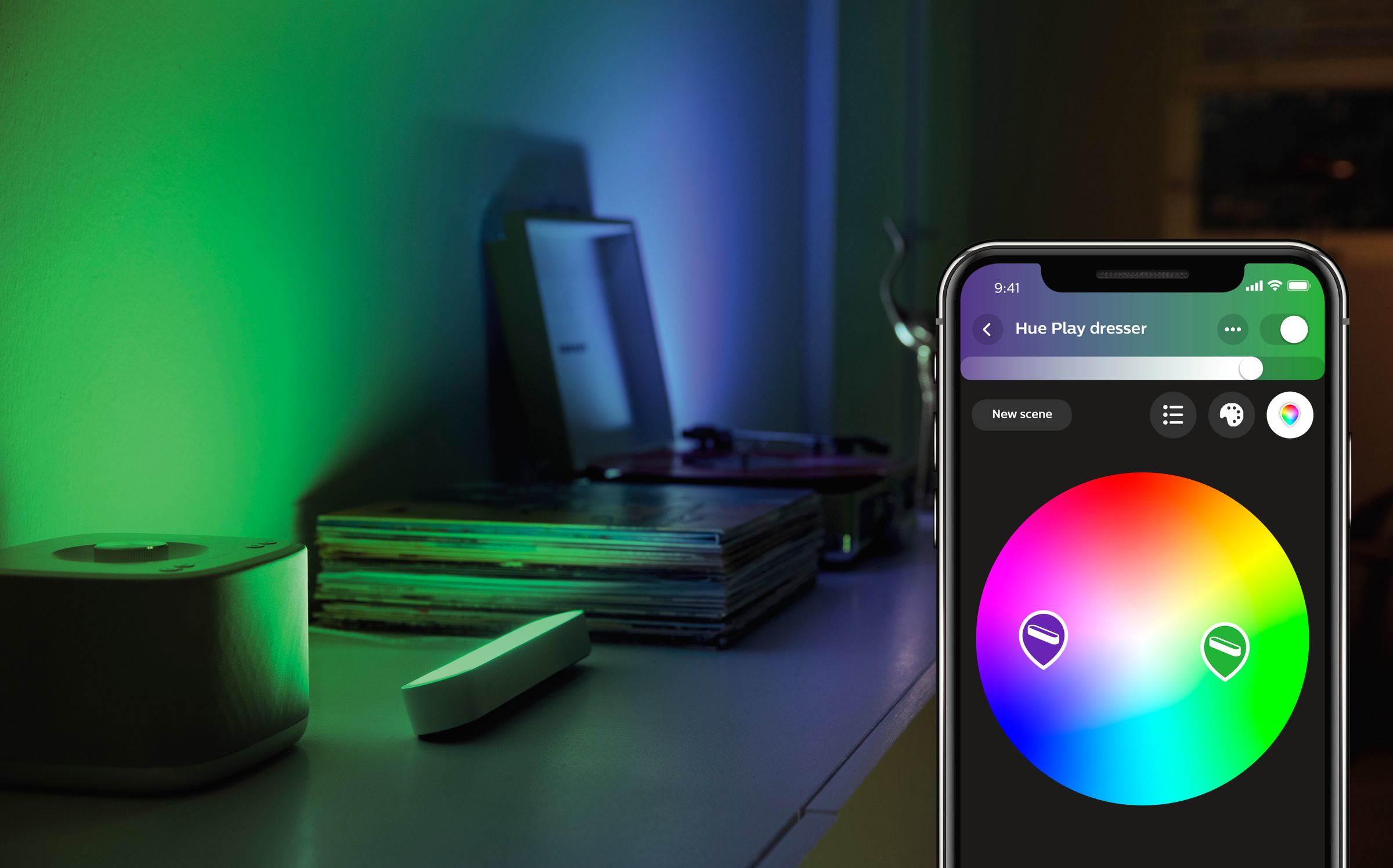 Smartphone with color wheel, a green and blue lit room, other objects on a white surface.