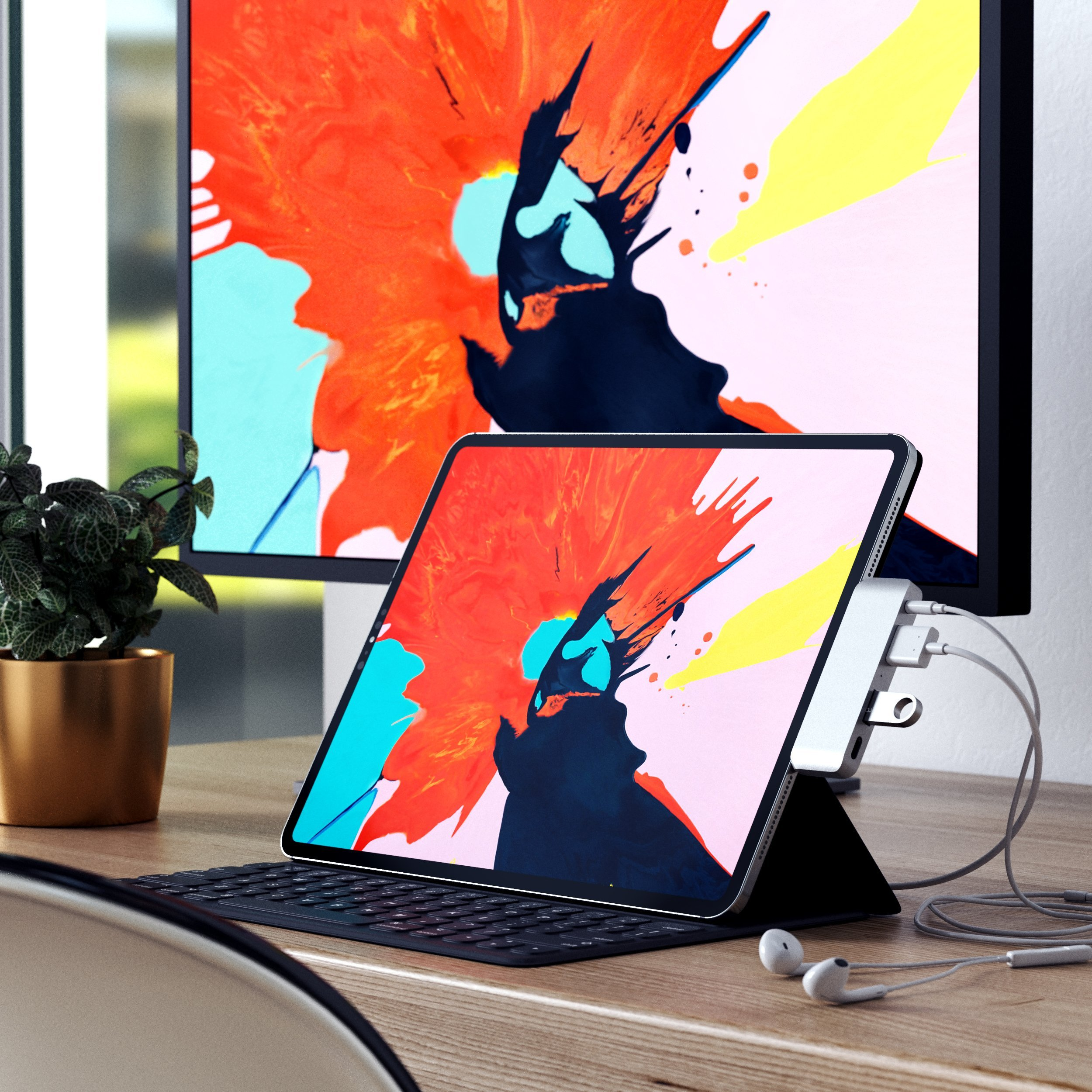 Ein iPad mit Tastatur und ein Monitor mit abstrakter Kunst.