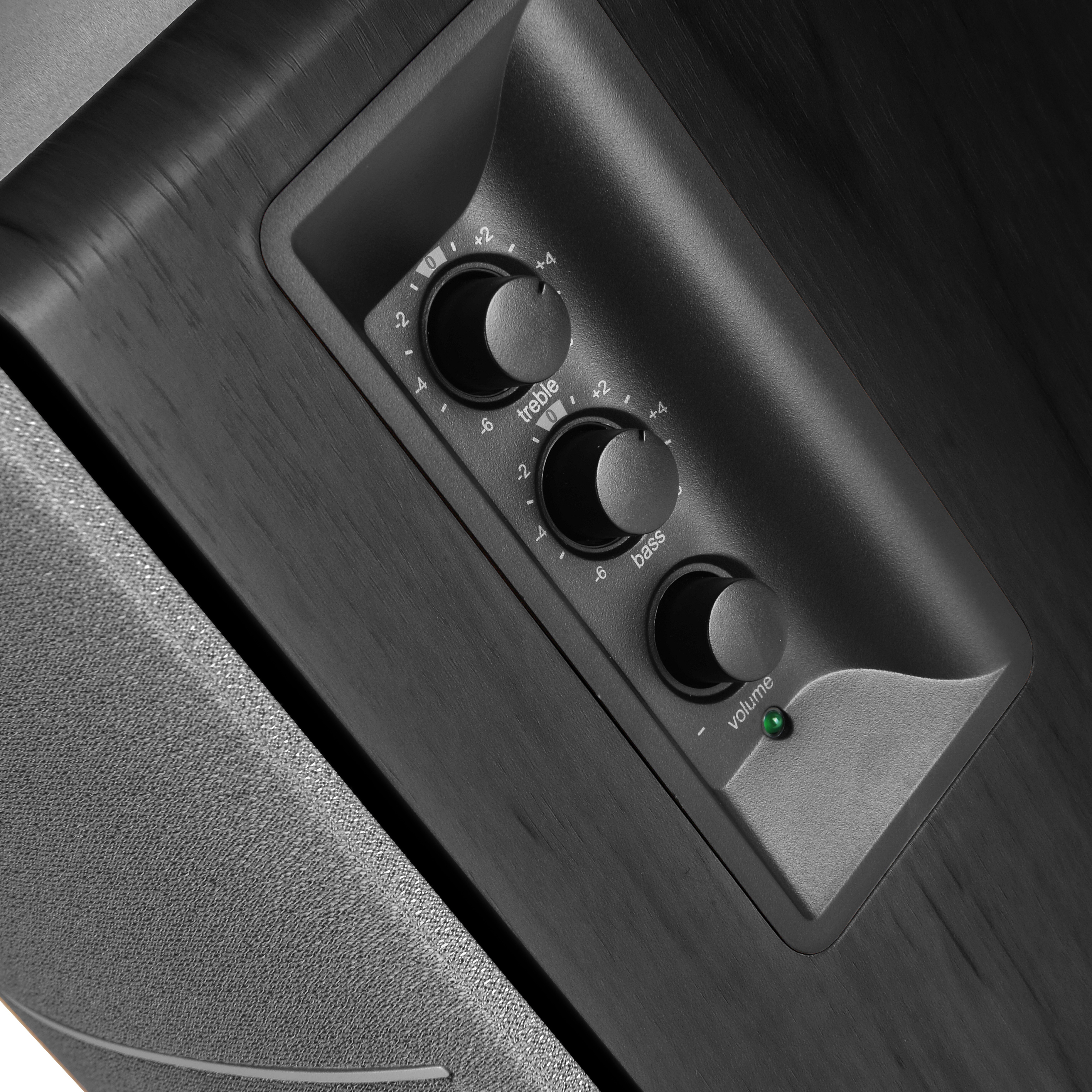 Nahaufnahme der Bedienelemente des Audiosystems: Höhen-, Bass- und Lautstärkeregler mit grüner Betriebsleuchte.