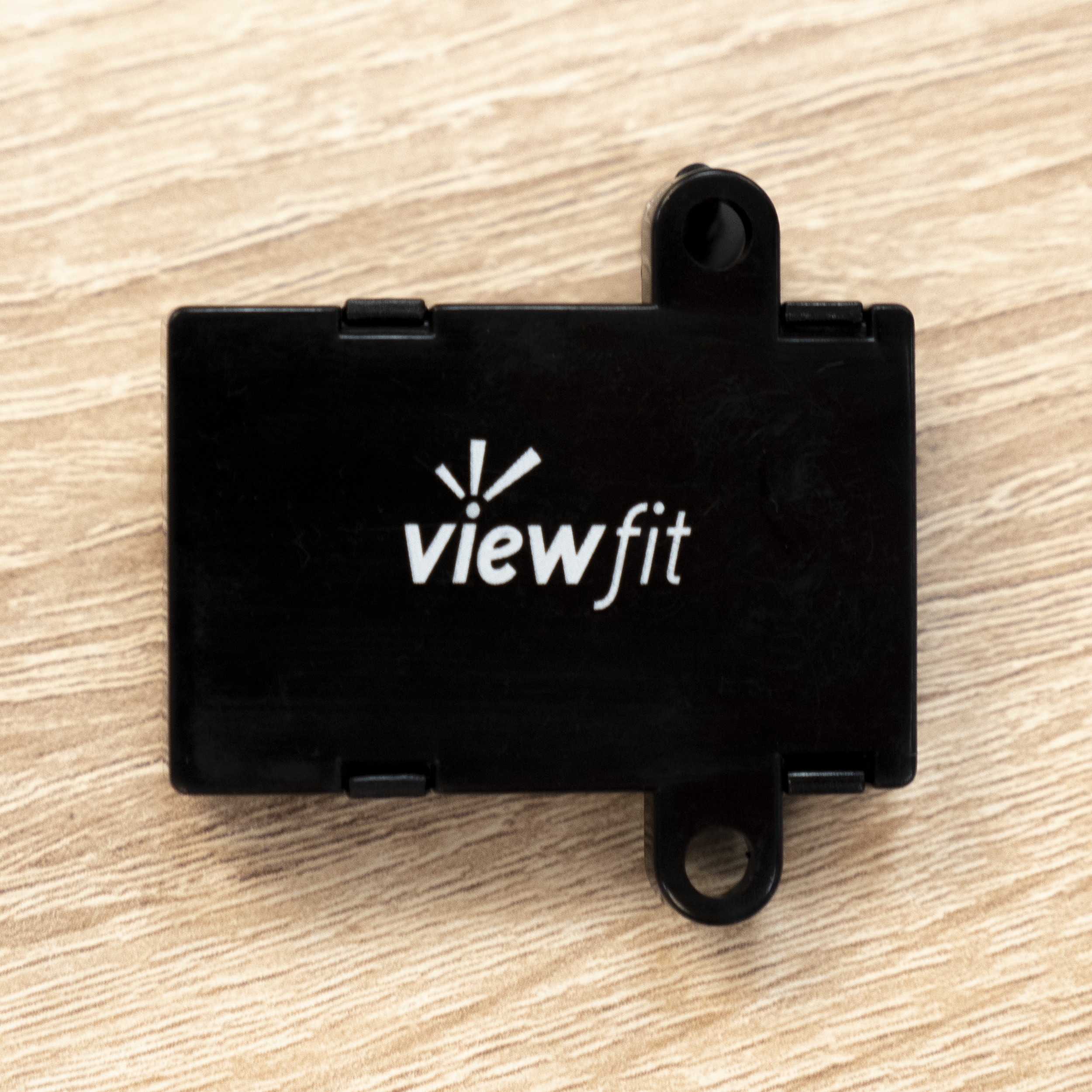Ein schwarzes, rechteckiges Viewfit-Gerät auf einer Holzoberfläche.